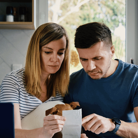 Couple Budgeting Sat At Table Looking At Receipt