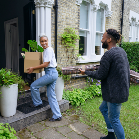 Couple moving boxes into their new house