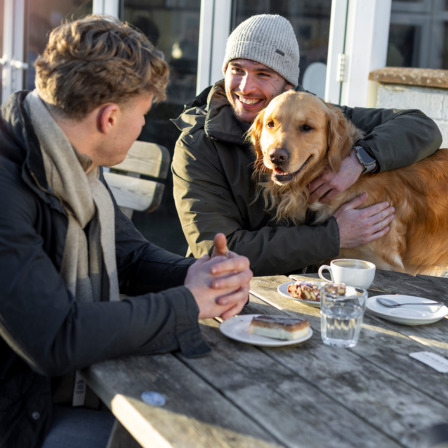 Two Men Talking At A Cafe With A Dog