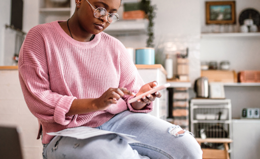 Lady at home wearing a pink jumper on her phone