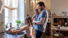 Father With Baby Watching Young Daughter With Chores Landscape