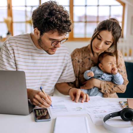 Family looking through their finances, mother is holding a young baby