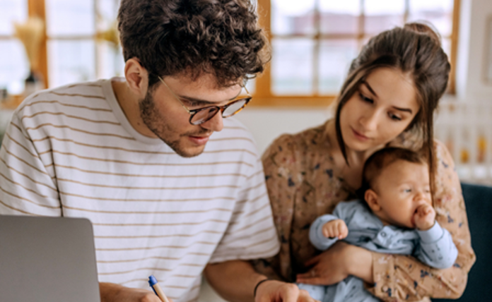 Family looking through their finances, mother is holding a young baby