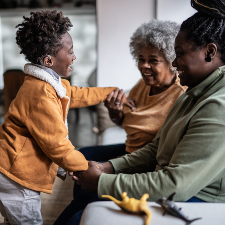 Child With Hearing Aid Hugging Family