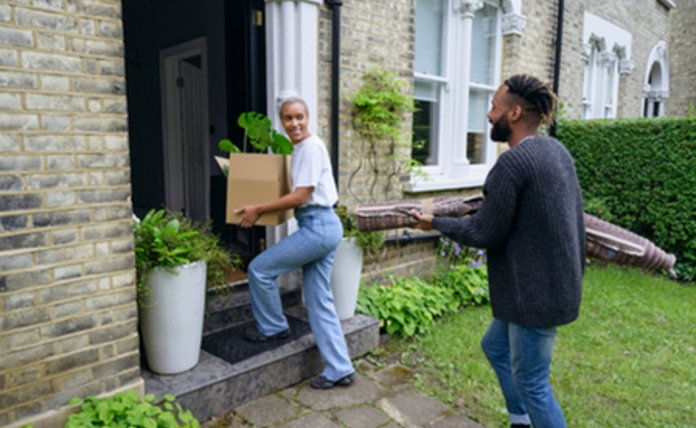Couple moving boxes into their new house