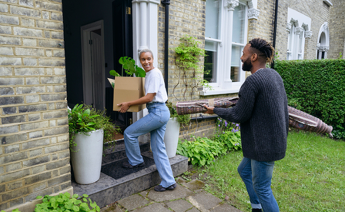 Couple moving boxes into their new house