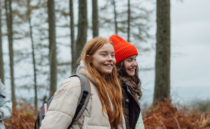 two teenage girls walking through the woods